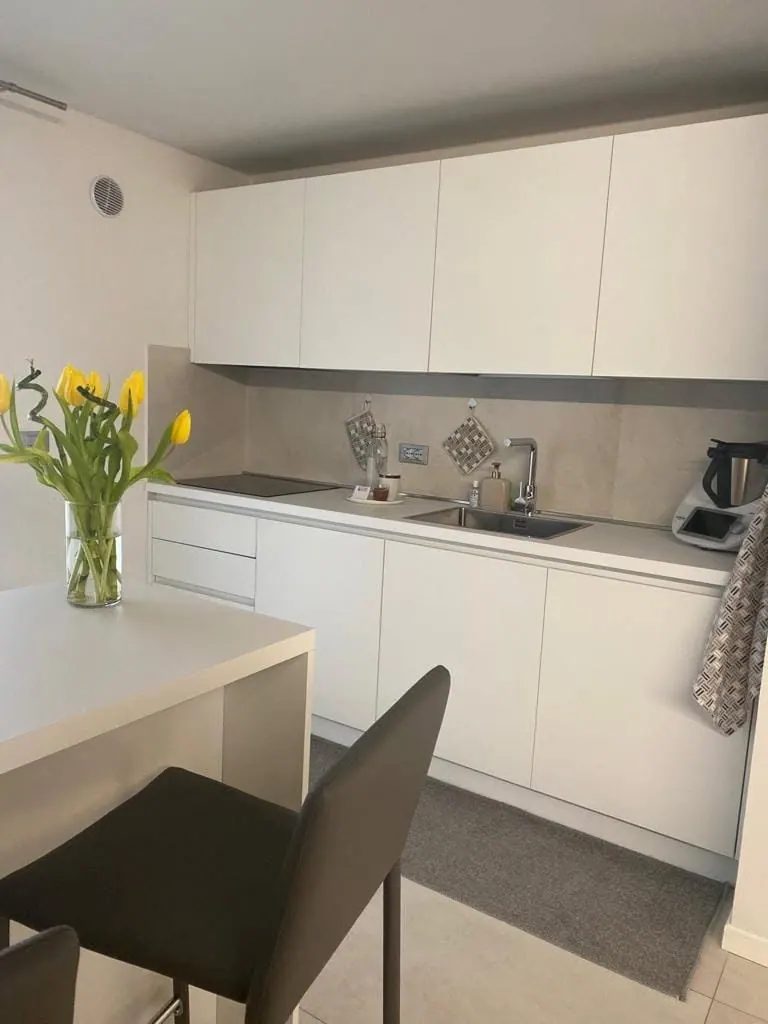 Appartamento: cucina bianca con penisola e tulipani