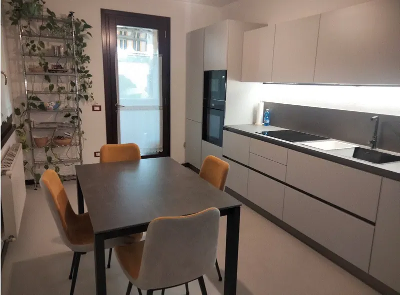 Cucina grigia lineare con tavolo e sedie color ocra