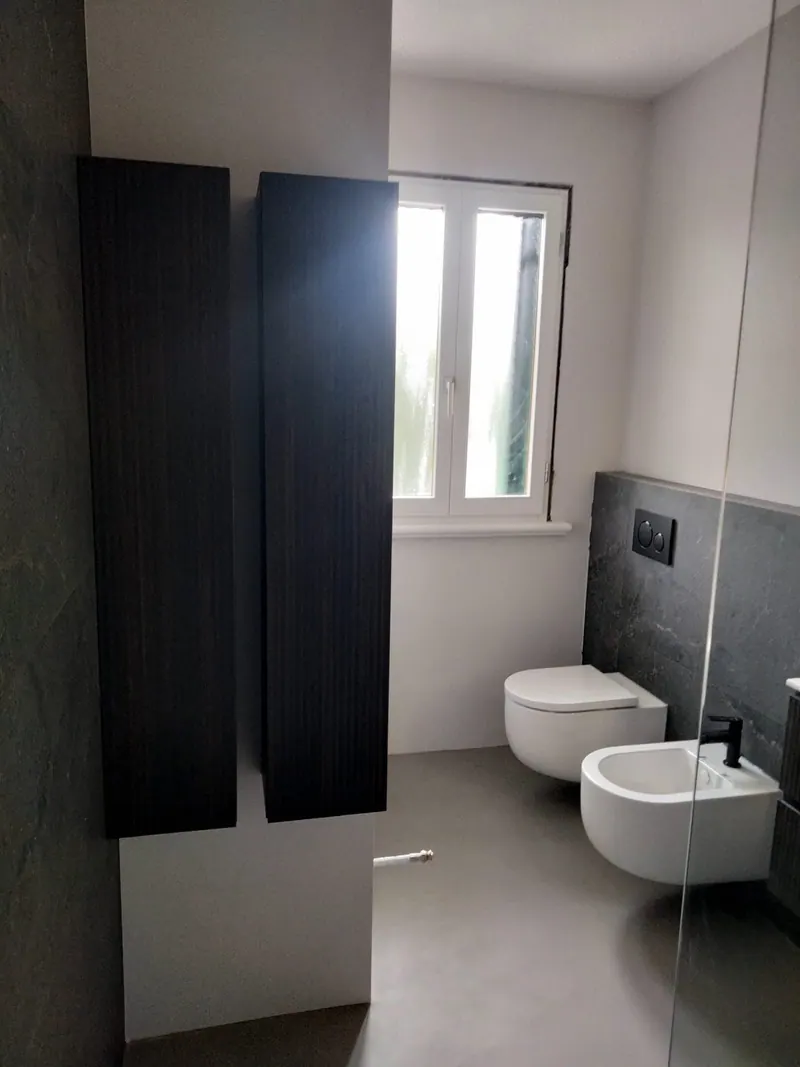 Lo stesso bagno: pensile scuro e sanitari sospesi