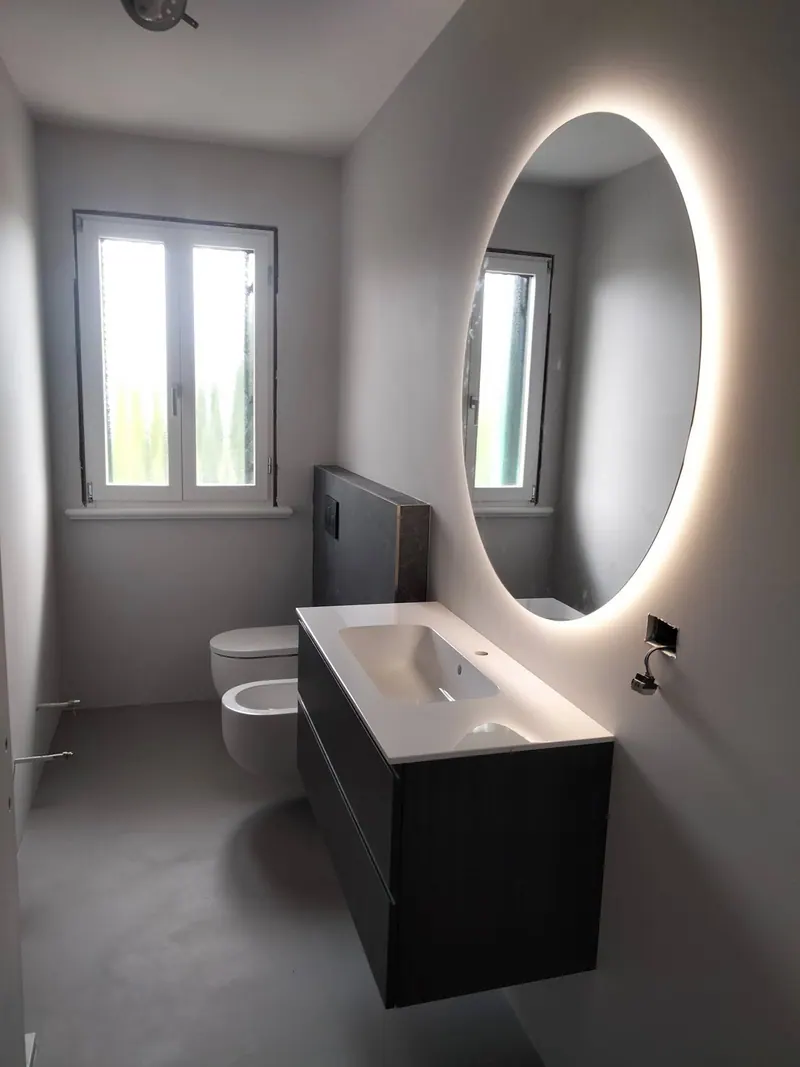Bagno con specchio tondo retroilluminato sopra il lavabo