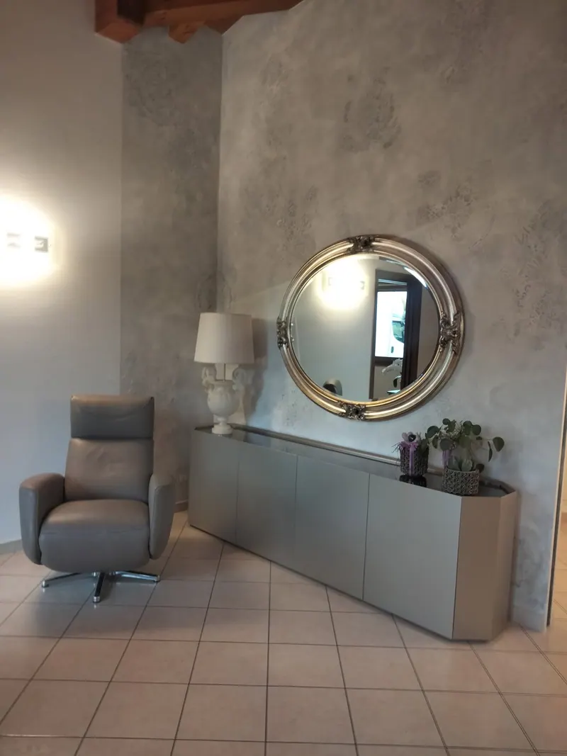 Ingresso con madia, specchio tondo e parete materica