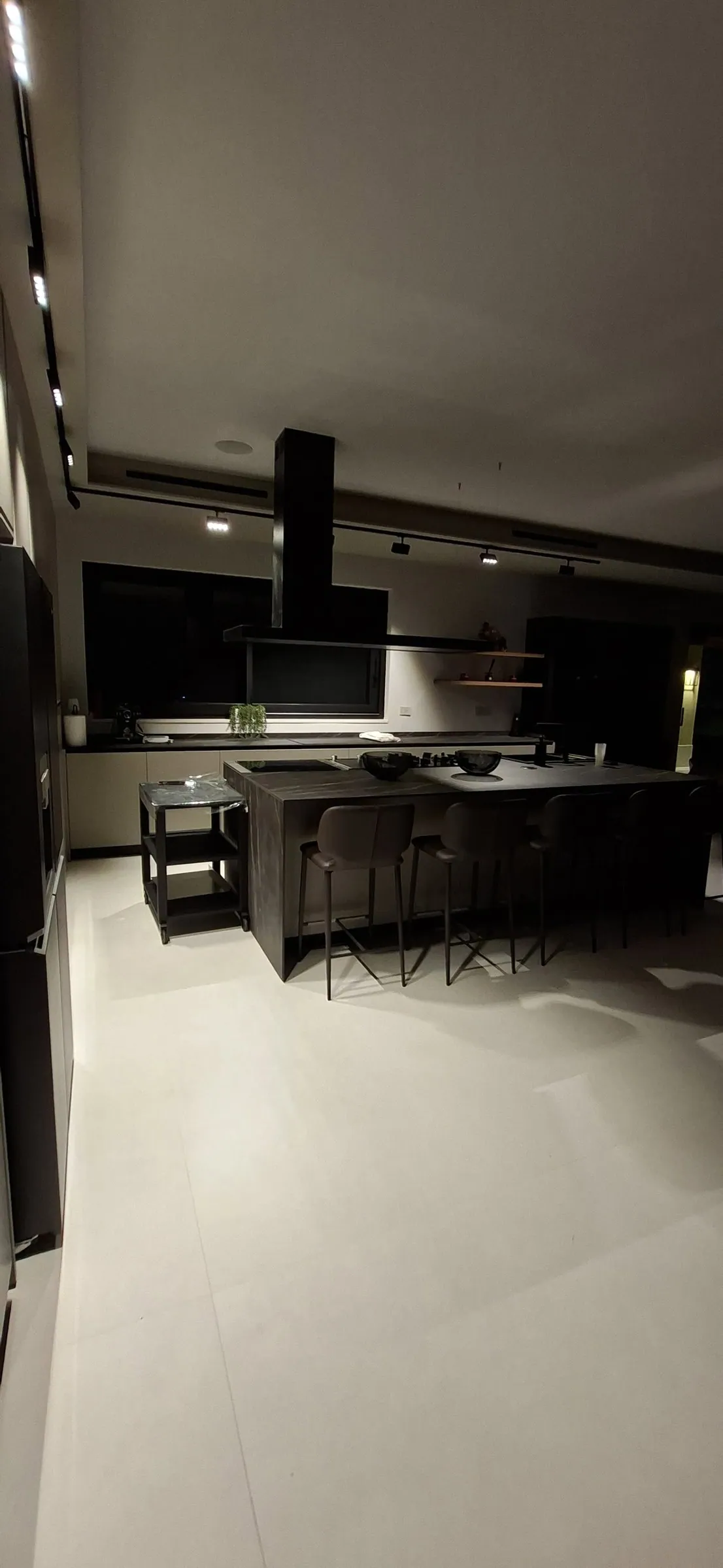 Cucina scura di una villa, con cappa a isola e luce calda