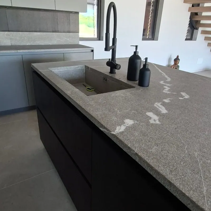 Cucina con isola scura: lavello ricavato nella pietra venata