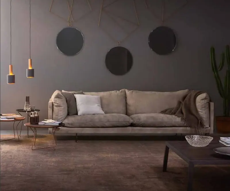 Divano beige e specchi tondi su una parete scura
