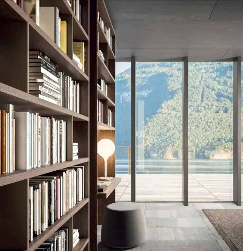 Libreria in legno scuro a tutta altezza davanti a una vetrata sul lago